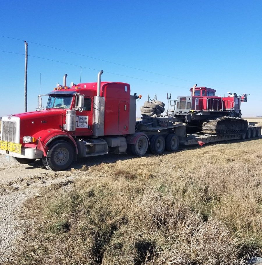 Semi truck hauling a tiling machine on a lowboy trailer